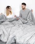 un couple dans un lit avec des couvertures lestées pour 2 personnes