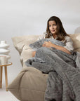 Une femme assise sur un canapé avec une couverture lestée haut de gamme balance grise