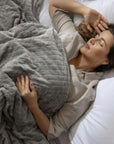Une femme allongée sur un lit avec une couverture lestée grise haut de gamme
