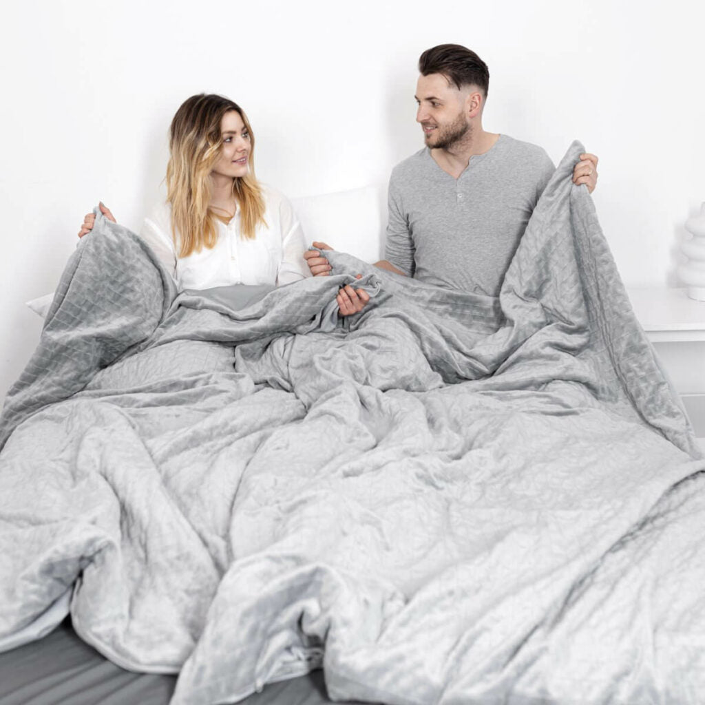 un couple dans un lit avec des couvertures lestées pour 2 personnes