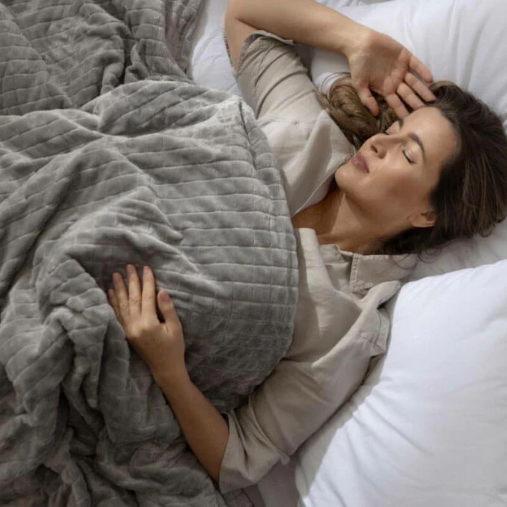 Une femme allongée sur un lit avec une couverture lestée grise haut de gamme