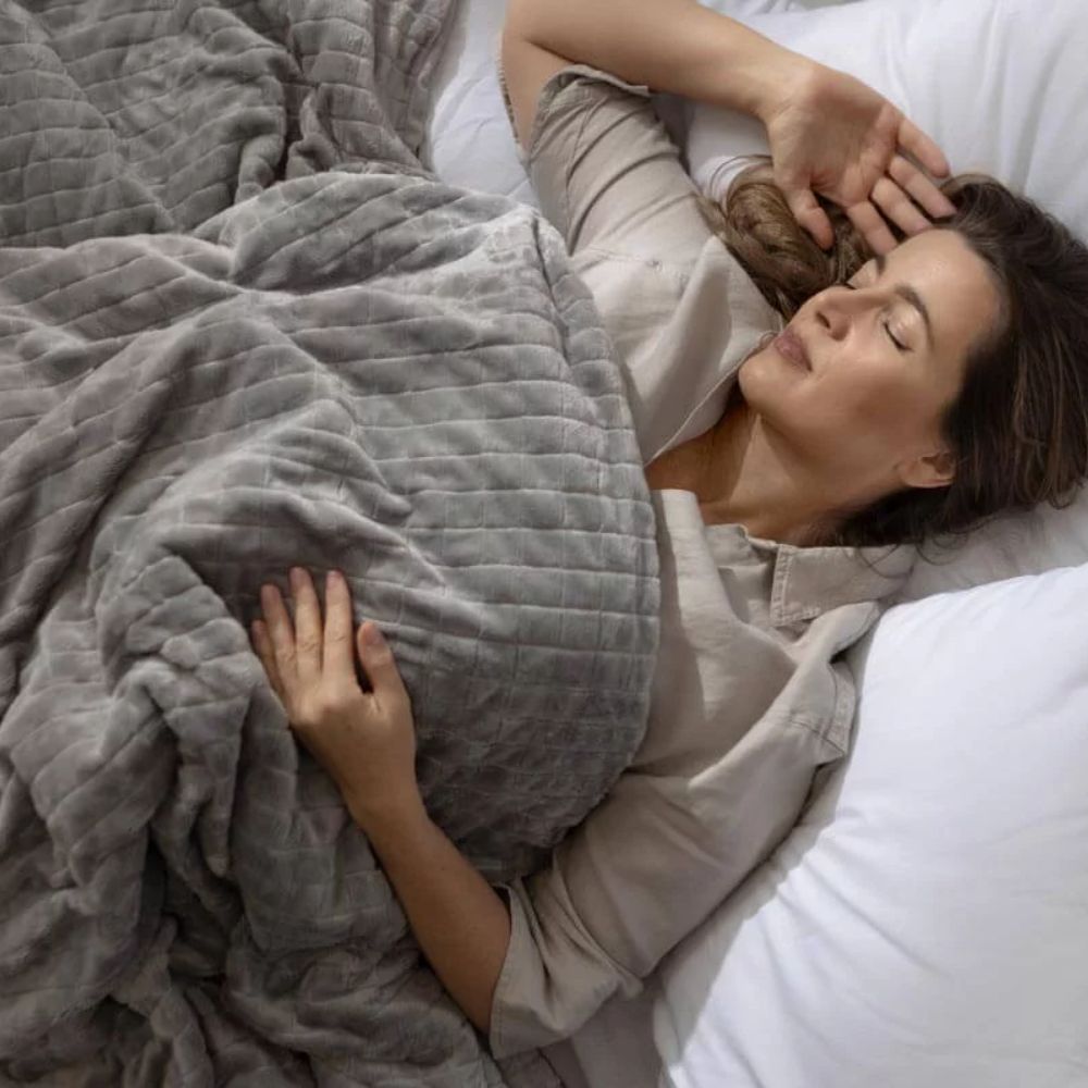 Femme sous une couverture lestée sur un lit