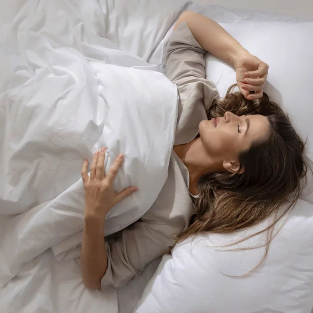 Femme sous une couverture lestée blanche sur un lit